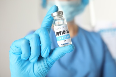 Photo of Doctor holding vial with vaccine against Covid-19 indoors, closeup