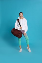 Photo of Beautiful woman with sports bag on light blue background