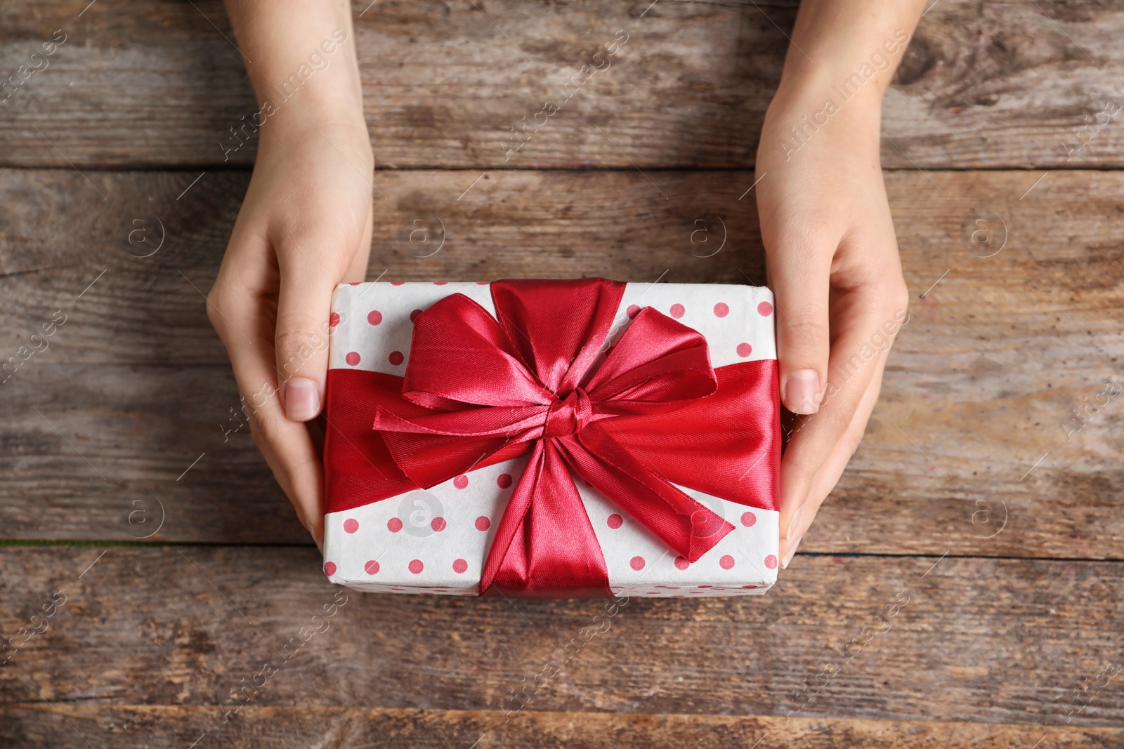 Photo of Woman with beautiful gift box on wooden background, top view