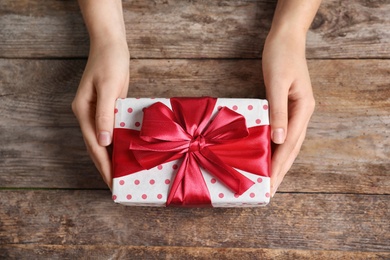 Photo of Woman with beautiful gift box on wooden background, top view