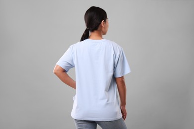 Photo of Woman wearing light blue t-shirt on grey background, back view