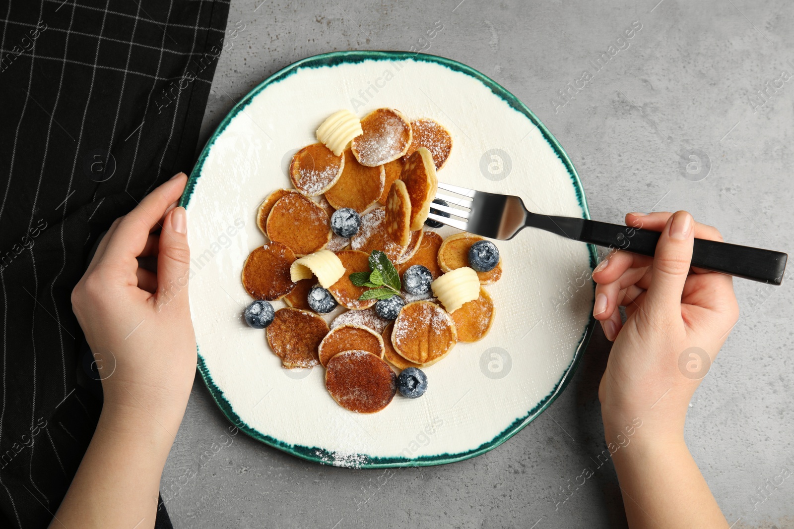 Photo of Woman eating cereal pancakes at light grey table, top view