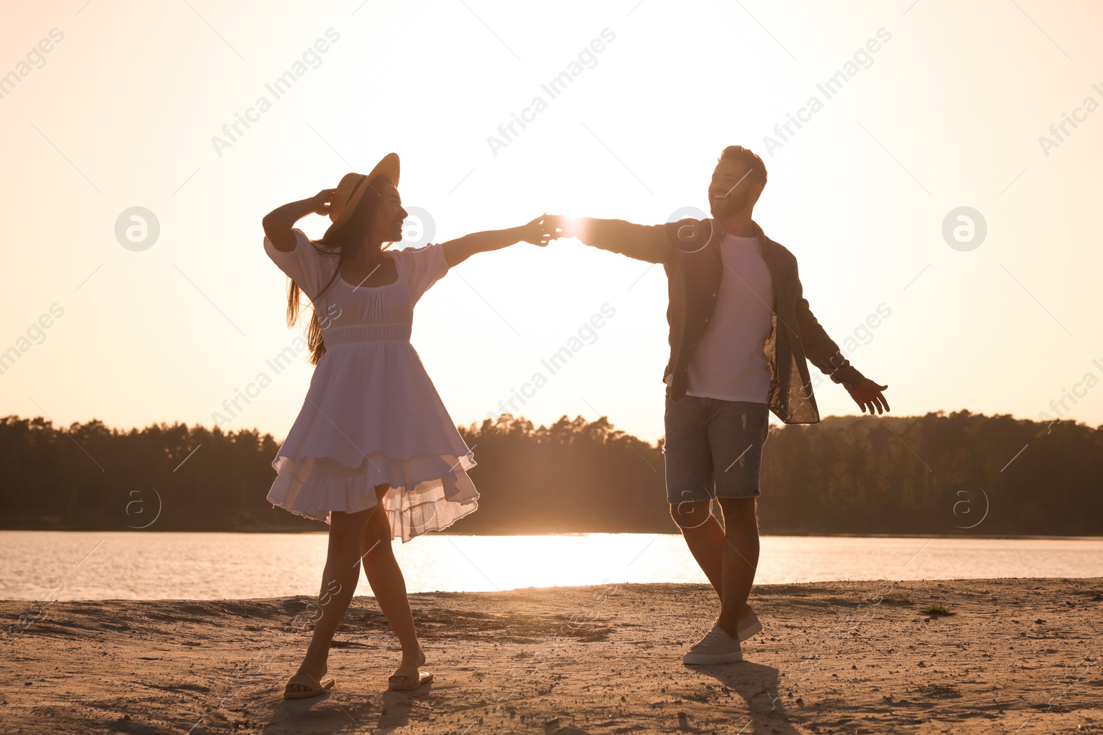 Photo of Happy couple dancing near river at sunset