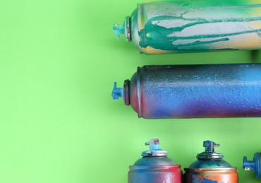Photo of Many spray paint cans on green background, flat lay. Space for text