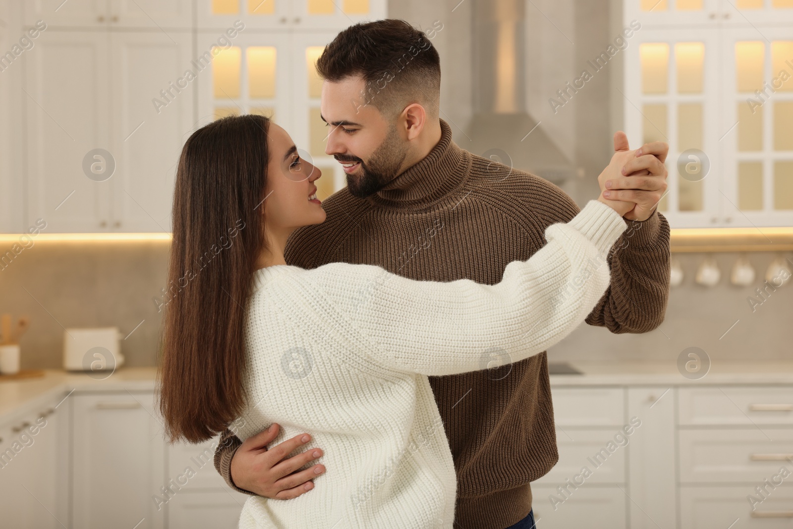 Photo of Affectionate young couple dancing in light kitchen