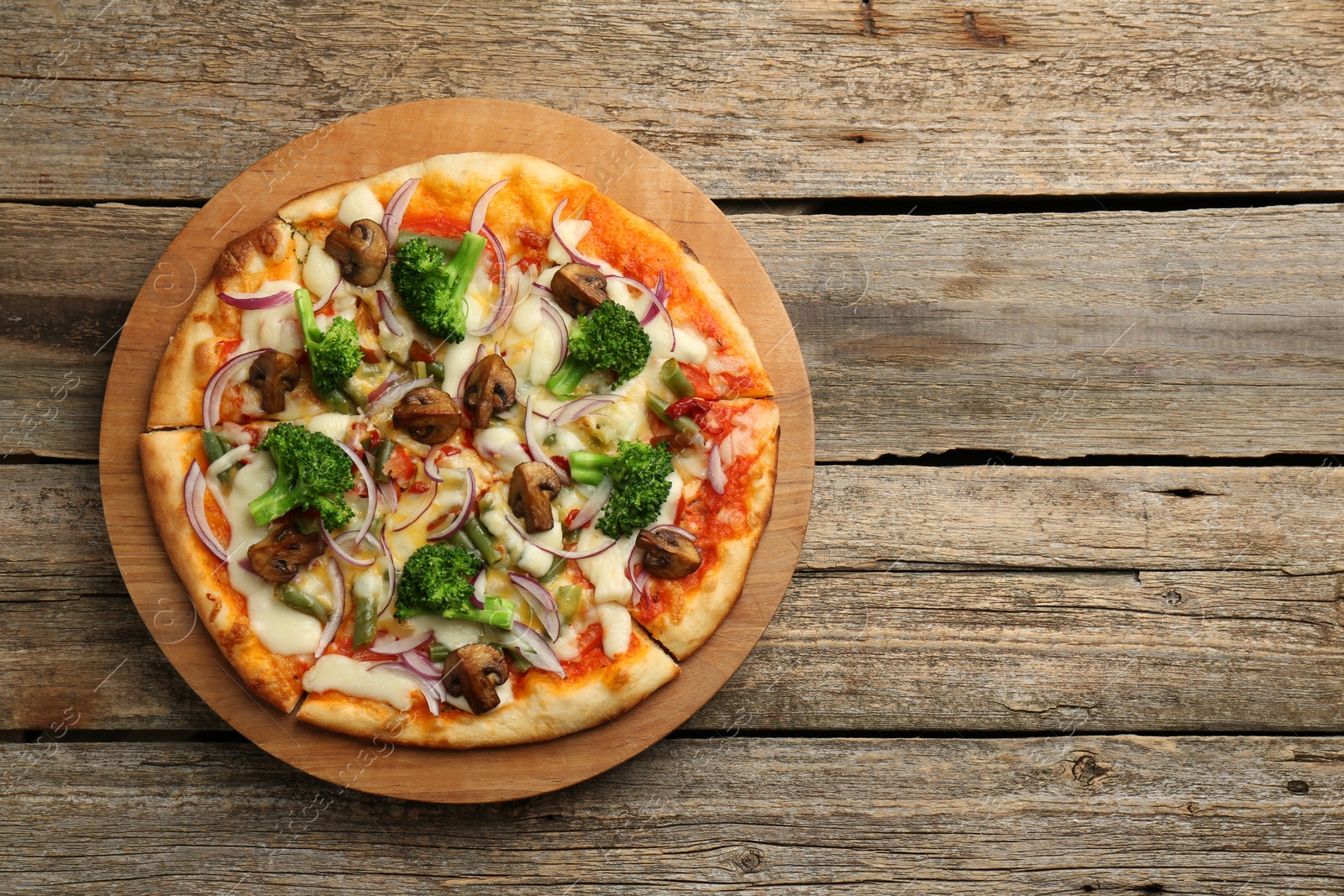 Photo of Board with delicious vegetarian pizza on wooden table, top view. Space for text