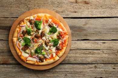 Photo of Board with delicious vegetarian pizza on wooden table, top view. Space for text