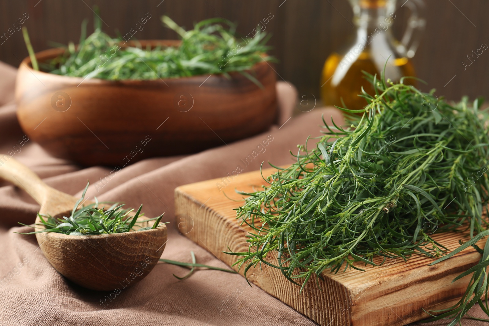 Photo of Fresh green tarragon sprigs on pink tablecloth