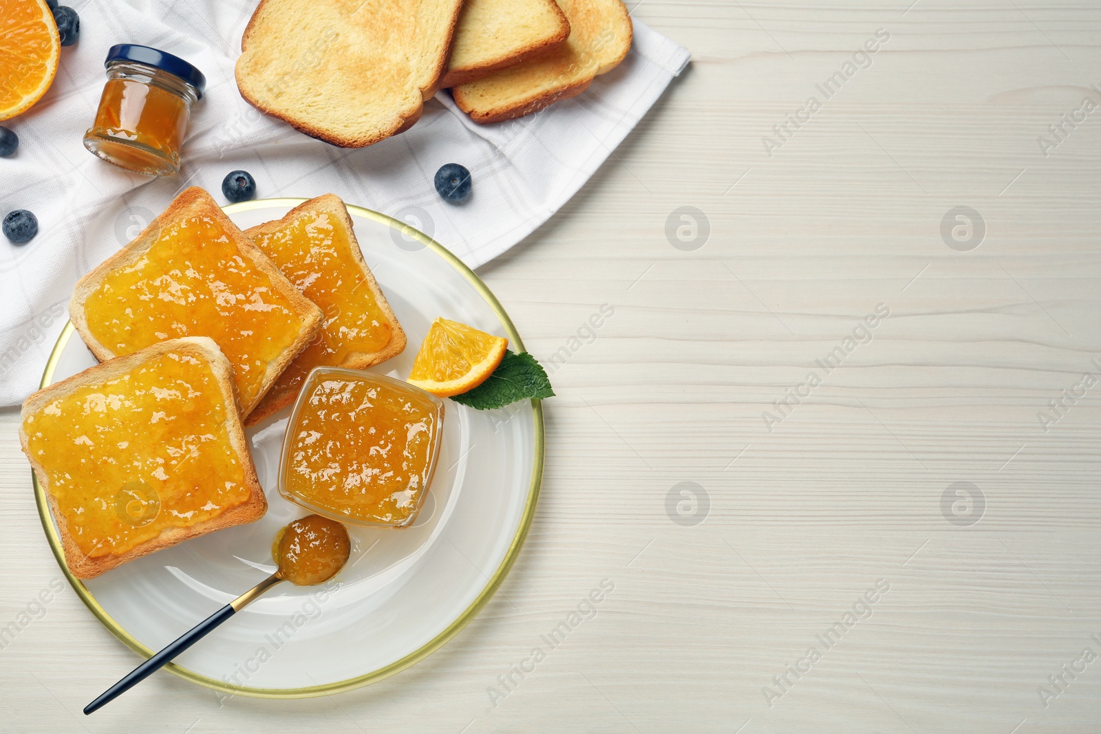 Photo of Delicious toasts with jam served on white wooden table, flat lay. Space for text