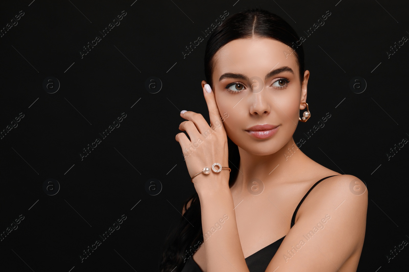 Photo of Young woman with elegant pearl jewelry on black background, space for text