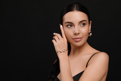 Photo of Young woman with elegant pearl jewelry on black background, space for text