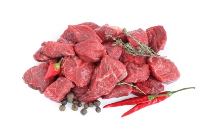 Photo of Pieces of raw beef meat, thyme sprigs, chili and peppercorns isolated on white, top view