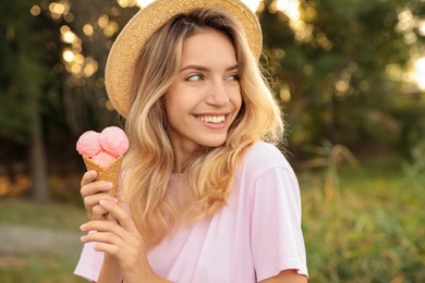 Happy young woman with delicious ice cream in waffle cone outdoors