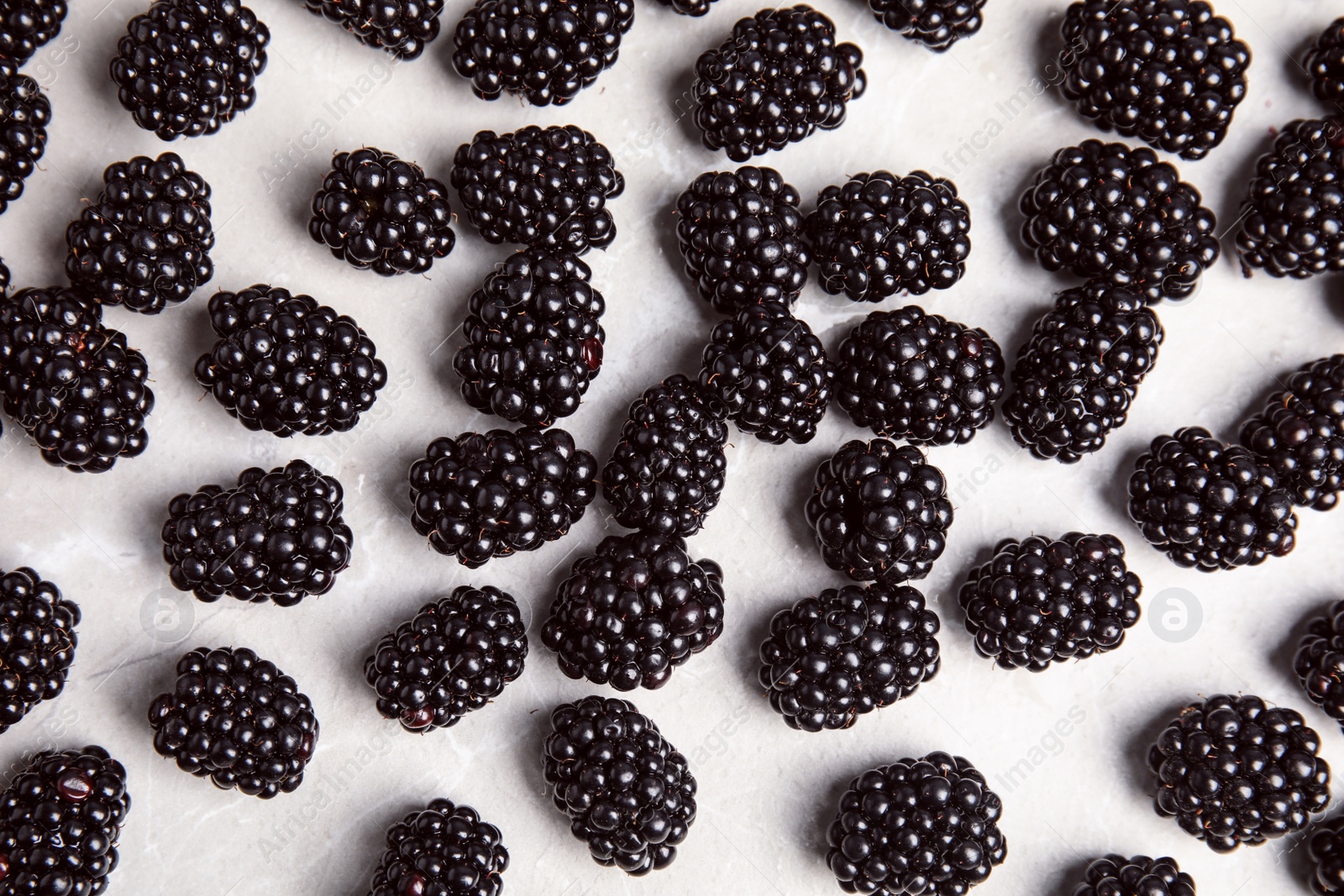 Photo of Tasty ripe blackberries on grey marble table, top view