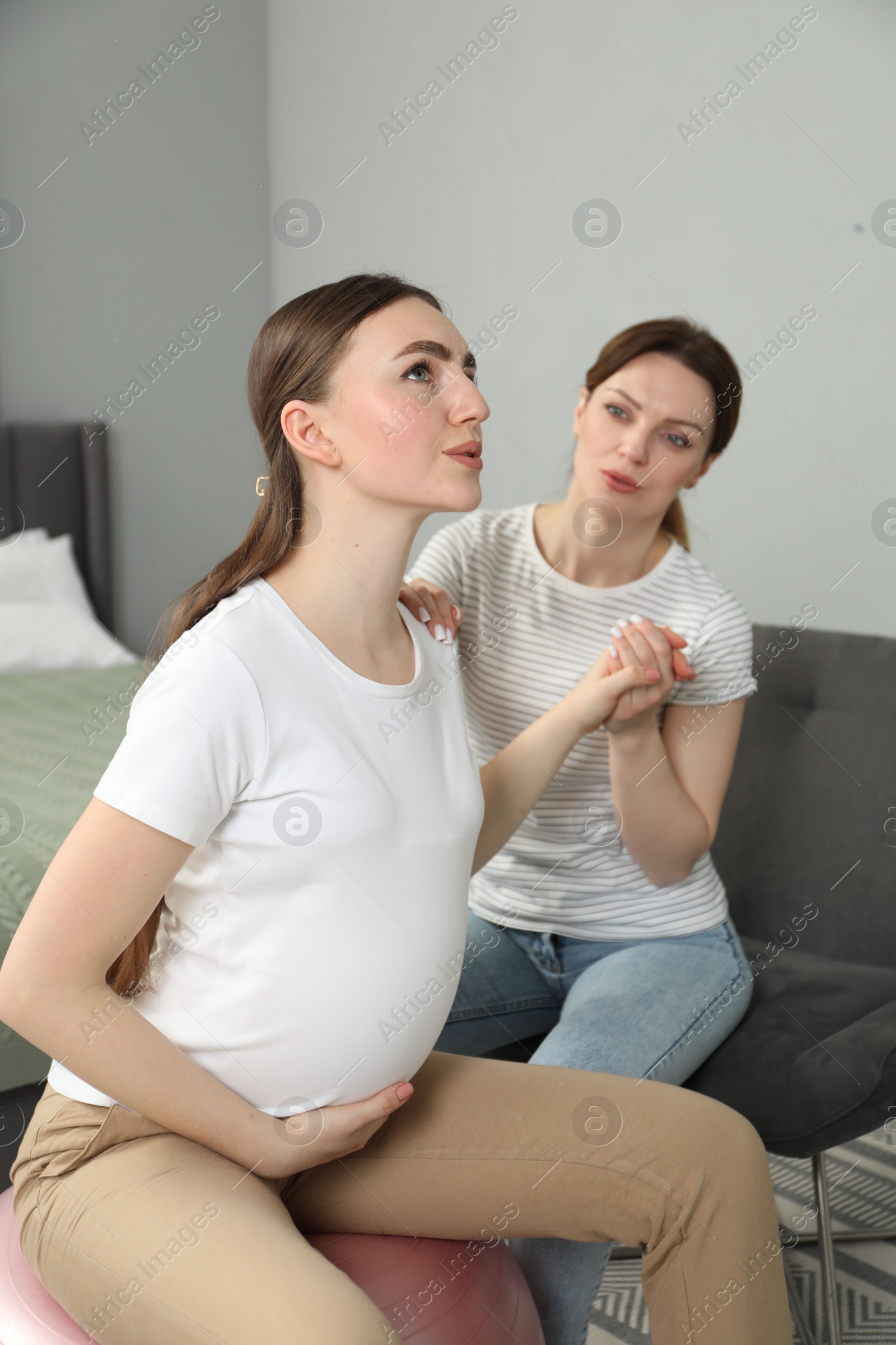 Photo of Doula taking care of pregnant woman in bedroom. Preparation for child birth