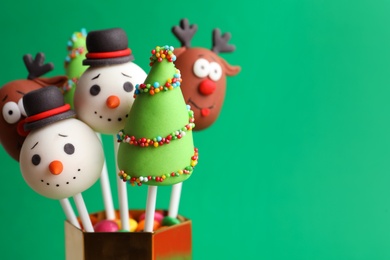 Delicious Christmas themed cake pops on green background, closeup. Space for text