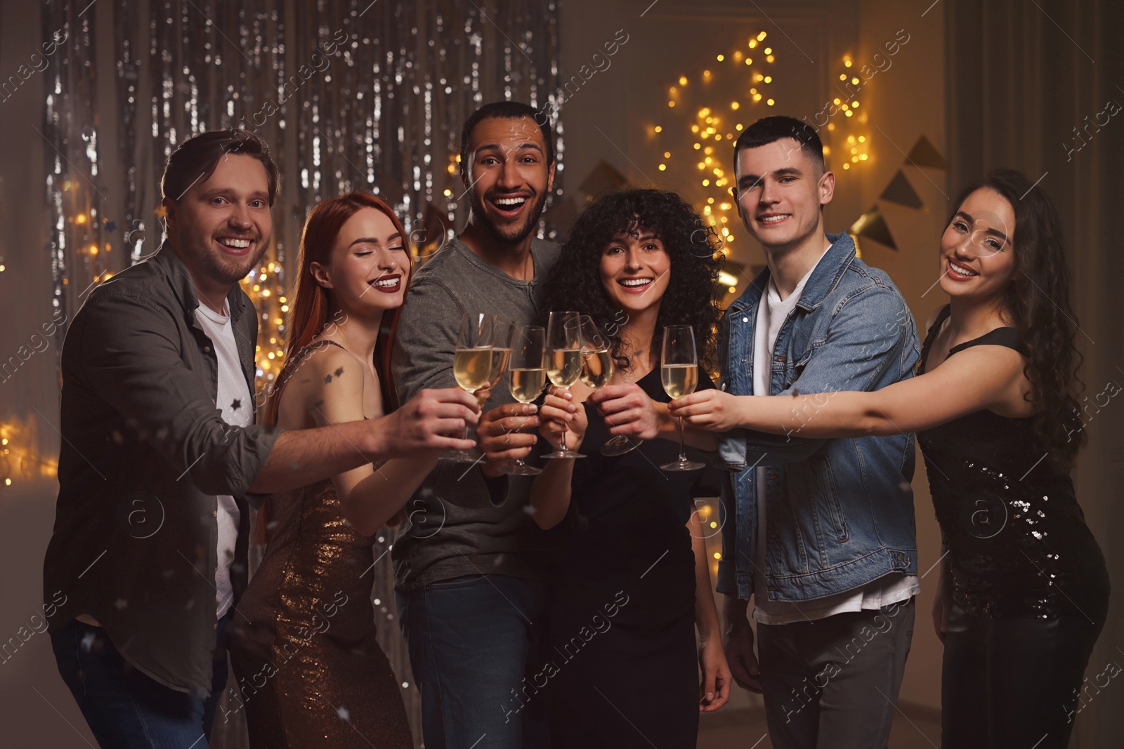 Photo of Happy friends with glasses of sparkling wine celebrating birthday indoors