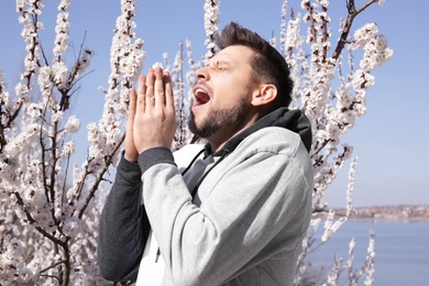 Photo of Man suffering from seasonal allergy outdoors on sunny day