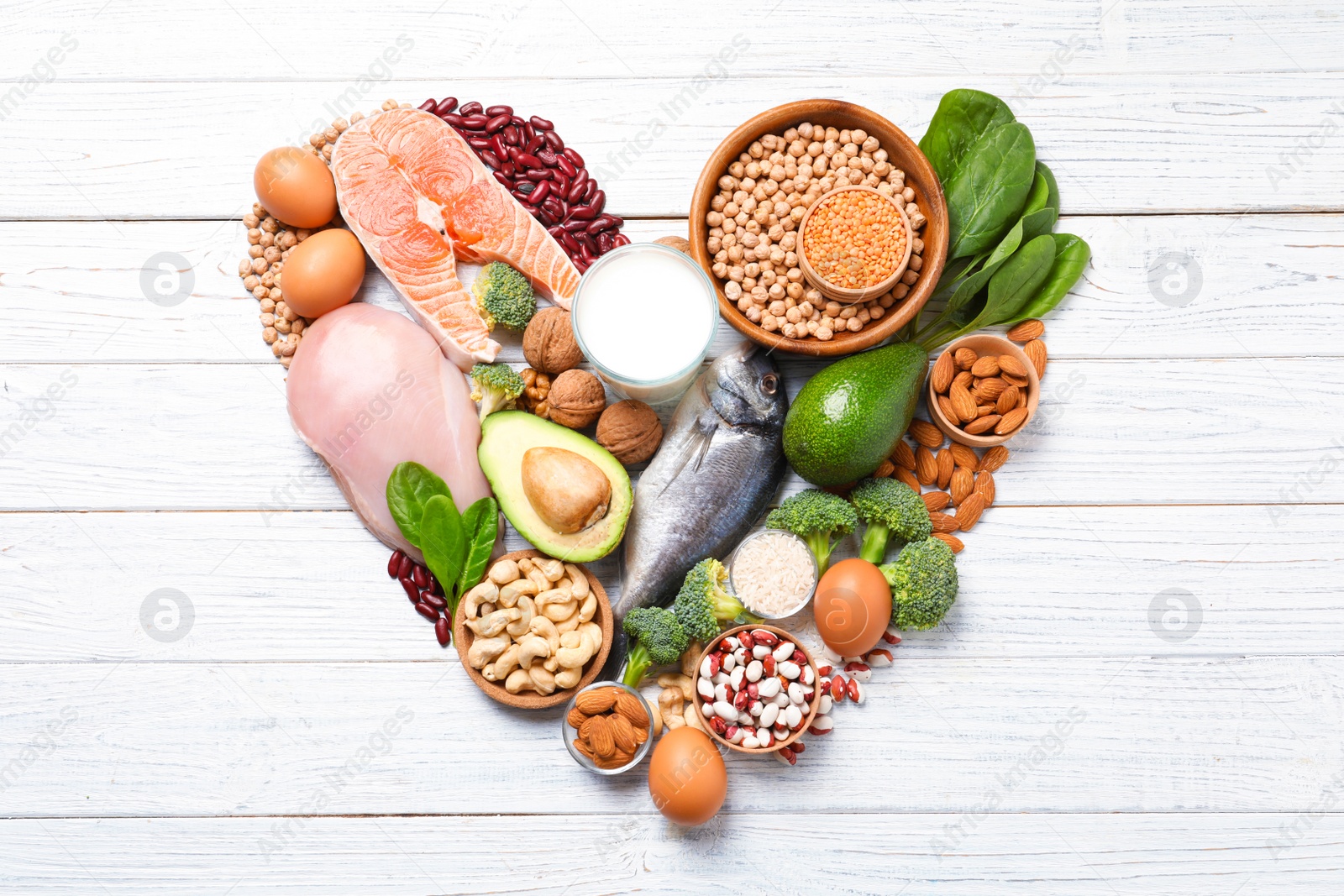 Photo of Heart shape made of natural food high in protein on white wooden background, top view