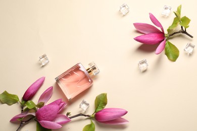 Beautiful pink magnolia flowers, bottle of perfume and ice cubes on beige background, flat lay