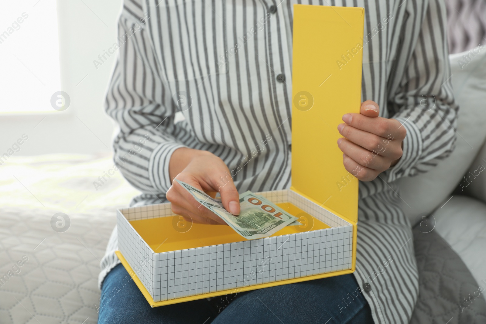 Photo of Woman hiding dollar banknotes in box at home, closeup. Money savings