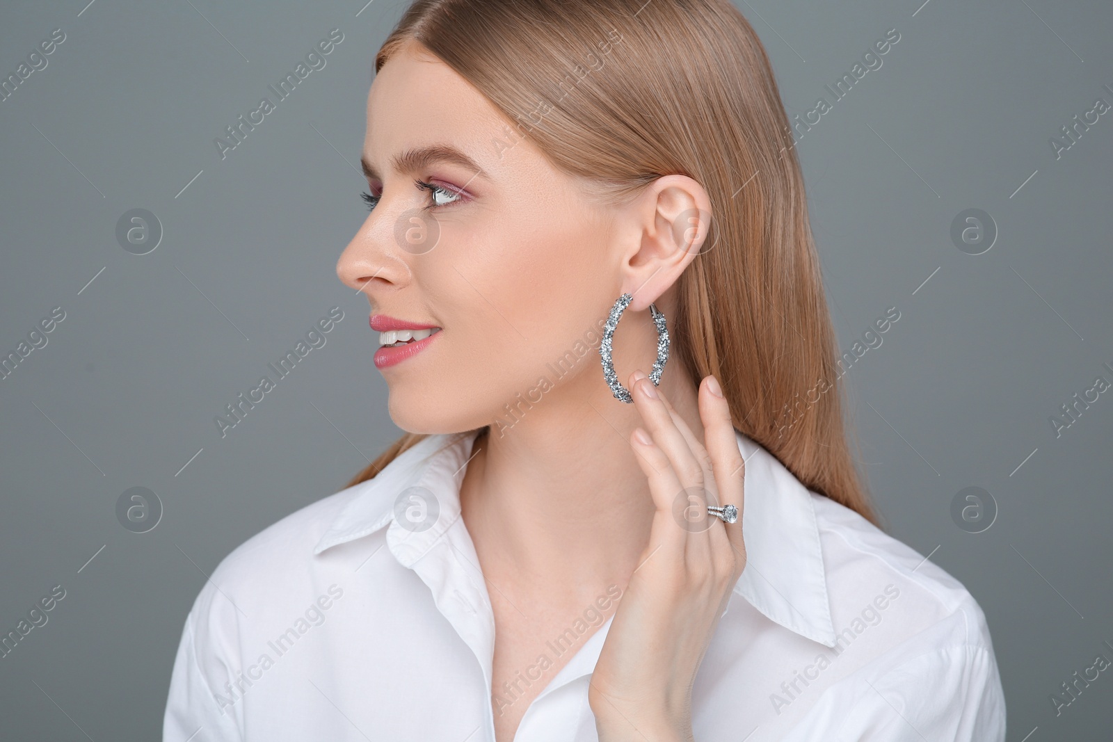 Photo of Beautiful young woman with elegant jewelry on gray background