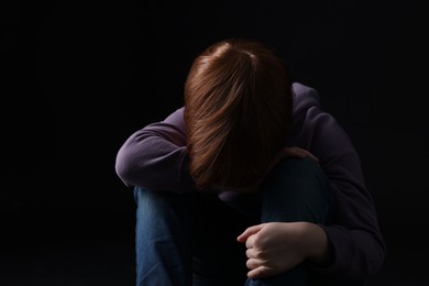 Photo of Portrait of sad little boy on black background