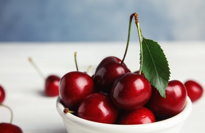 Photo of Bowl with sweet cherries on white table, closeup