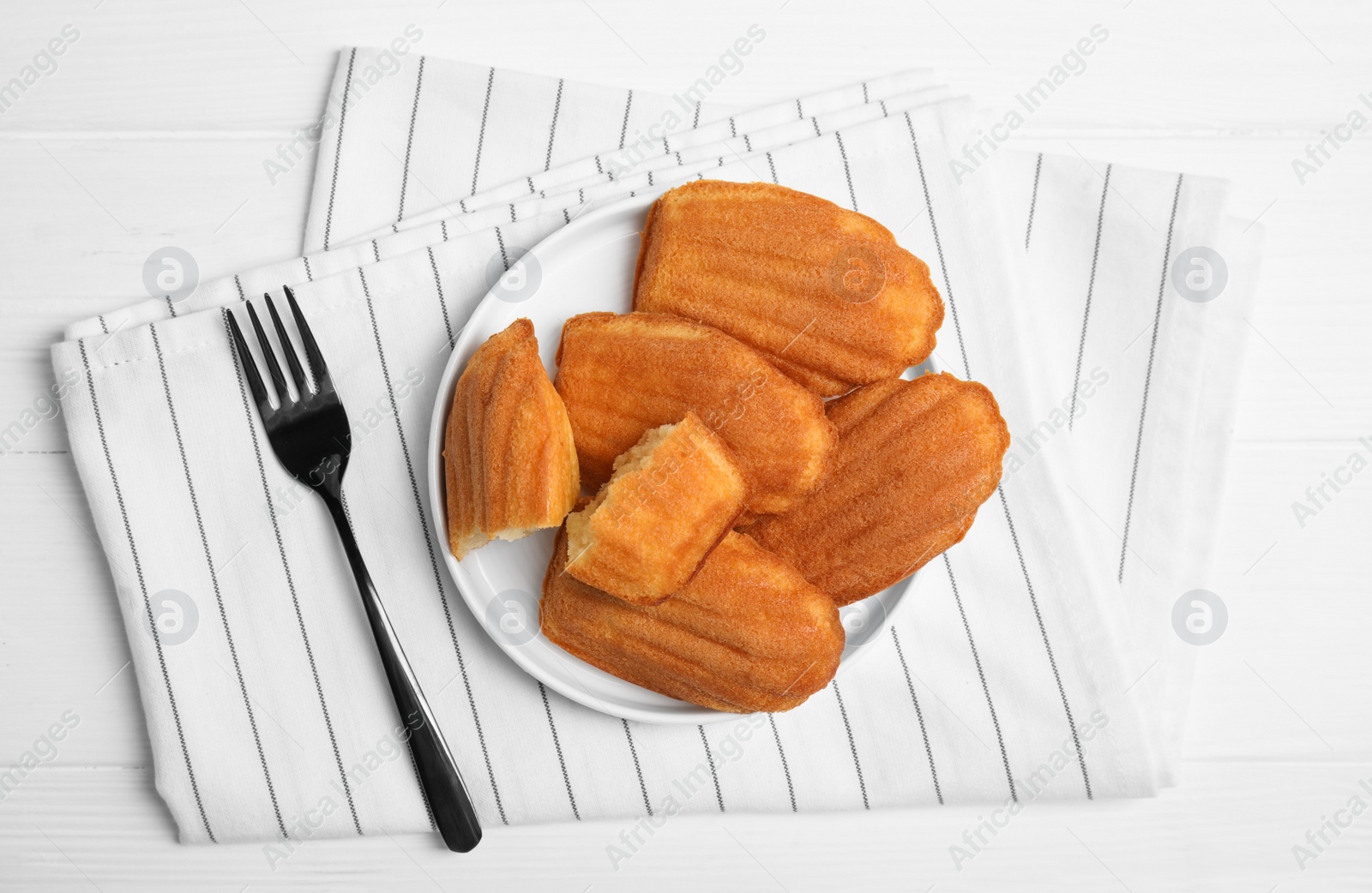 Photo of Delicious madeleine cakes on white wooden table, flat lay