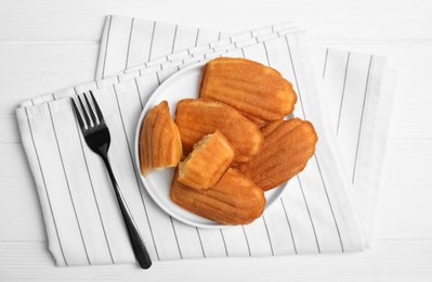 Delicious madeleine cakes on white wooden table, flat lay