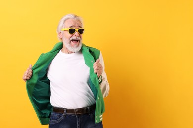 Portrait of grandpa with stylish sunglasses on yellow background, space for text