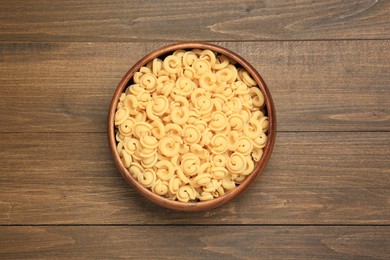 Raw dischi volanti pasta in bowl on wooden table, top view