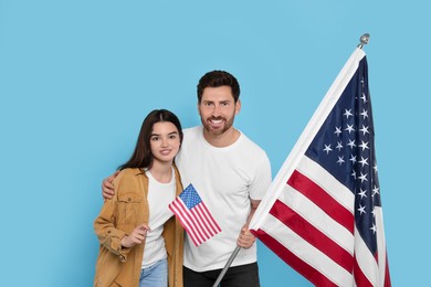 Photo of 4th of July - Independence Day of USA. Happy man and his daughter with American flags on light blue background