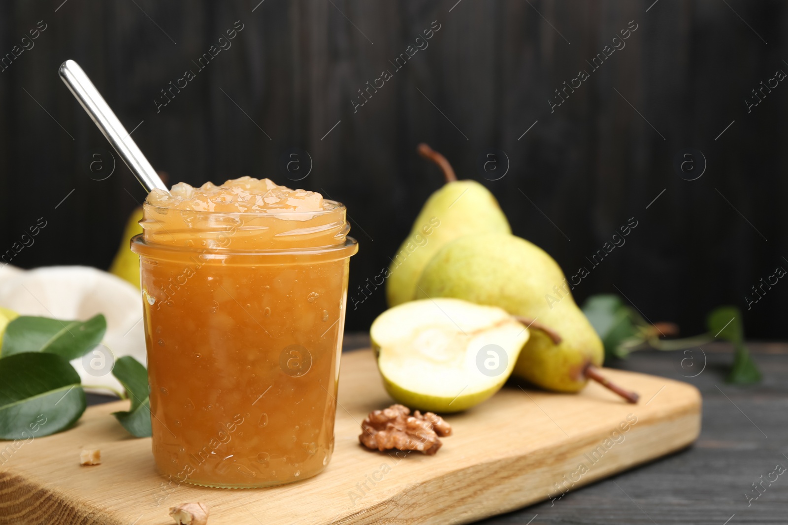 Photo of Delicious pear jam and fresh fruits on black table. Space for text
