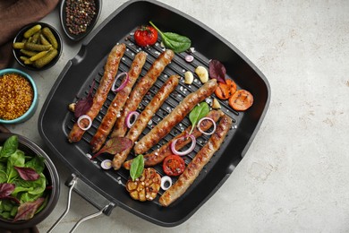 Grill pan with tasty sausages, spices and vegetables on light table, flat lay