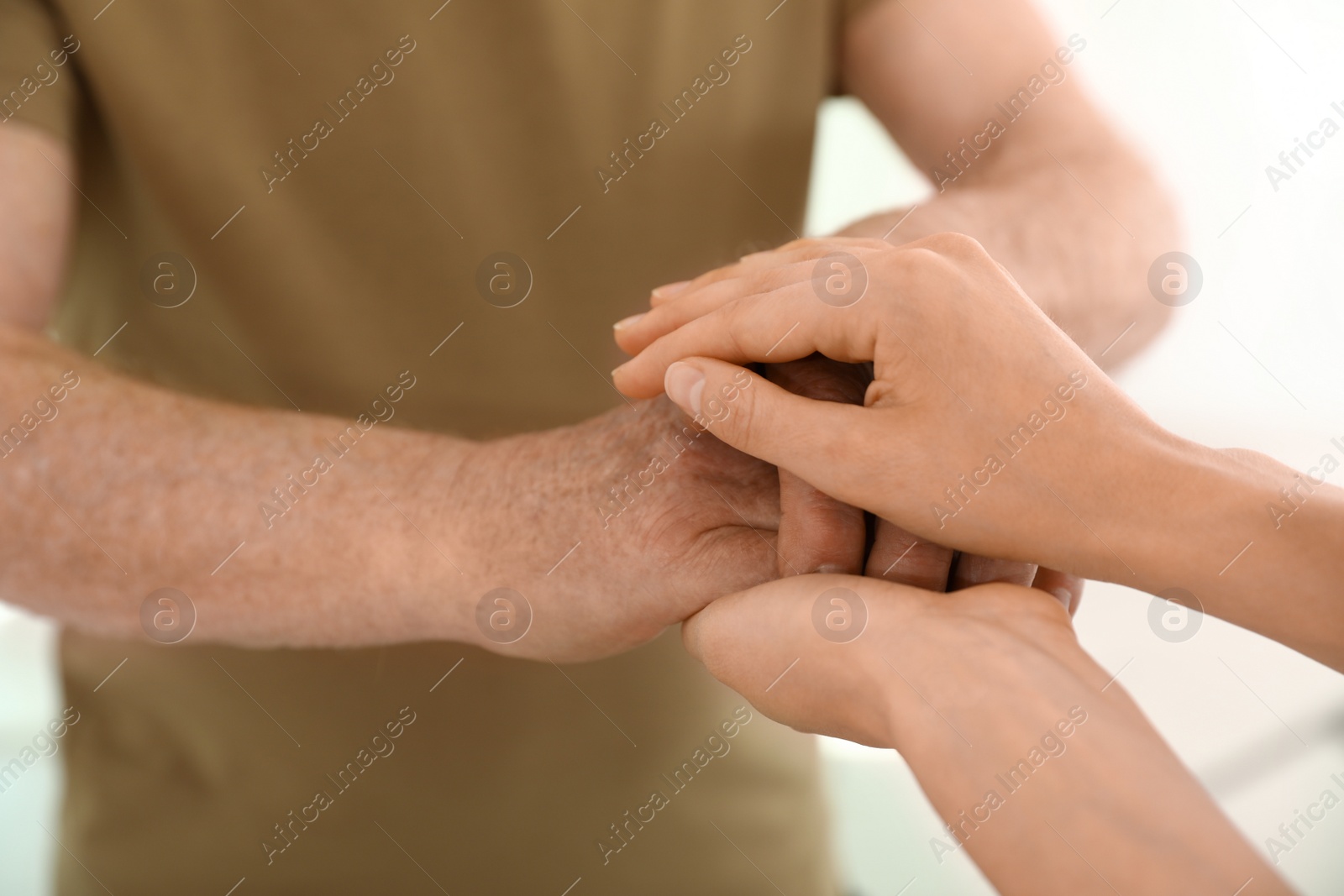 Photo of People holding hands together on blurred background, closeup. Help and elderly care concept