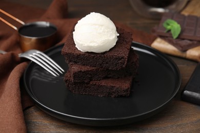 Photo of Tasty brownies served with ice cream on wooden table, closeup