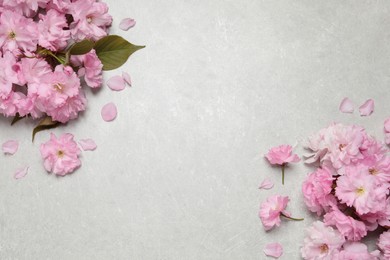 Photo of Beautiful sakura tree blossoms on grey stone table, flat lay. Space for text