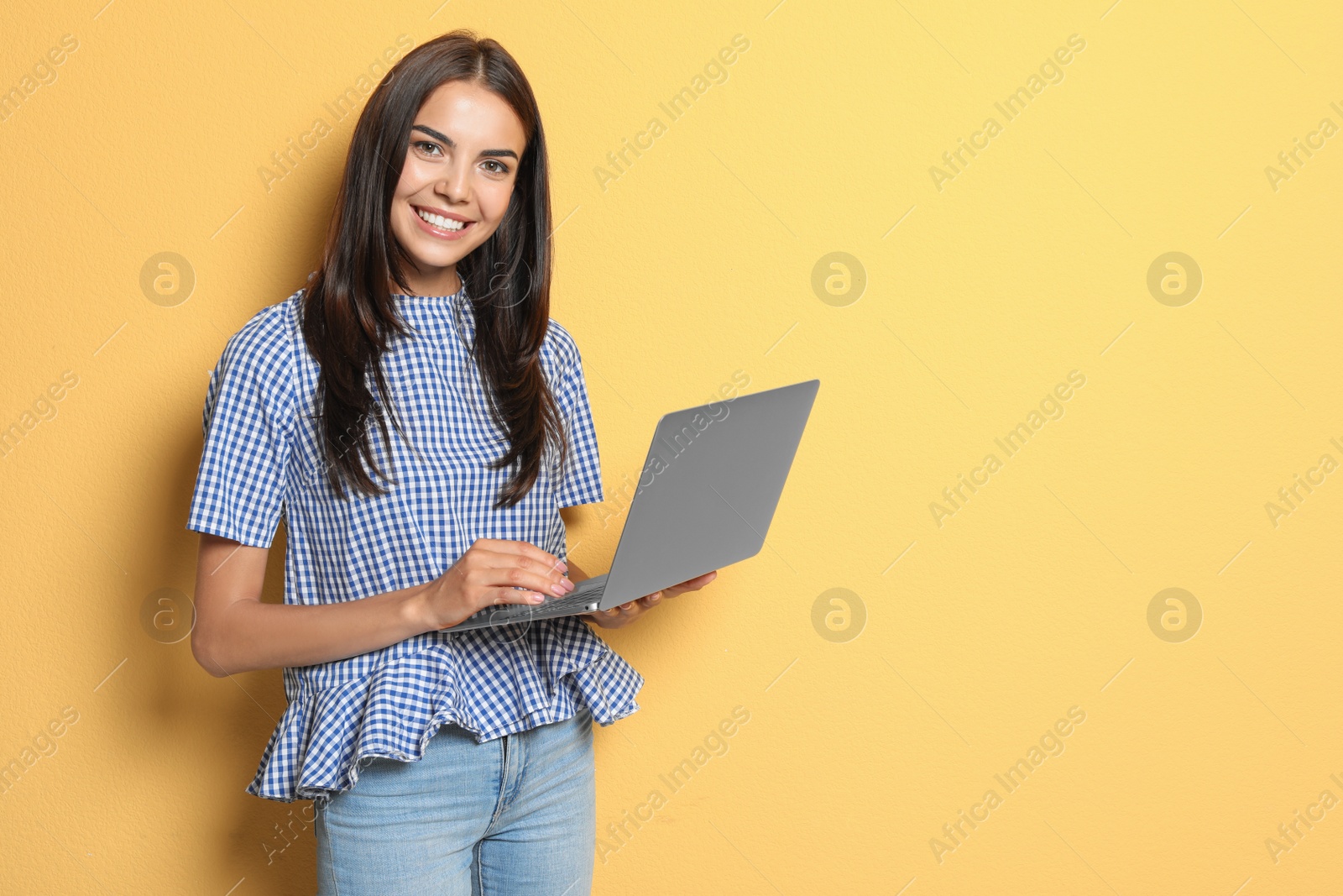 Photo of Young woman with modern laptop on color background