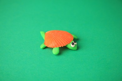 Photo of Turtle made from plasticine on green background. Children's handmade ideas