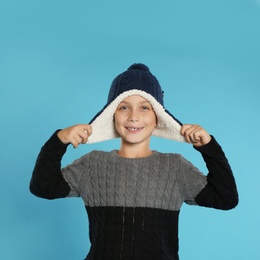 Photo of Cute little boy in sweater and hat on blue background. Winter season