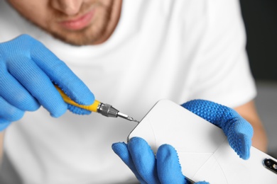 Technician repairing mobile phone with screwdriver, closeup