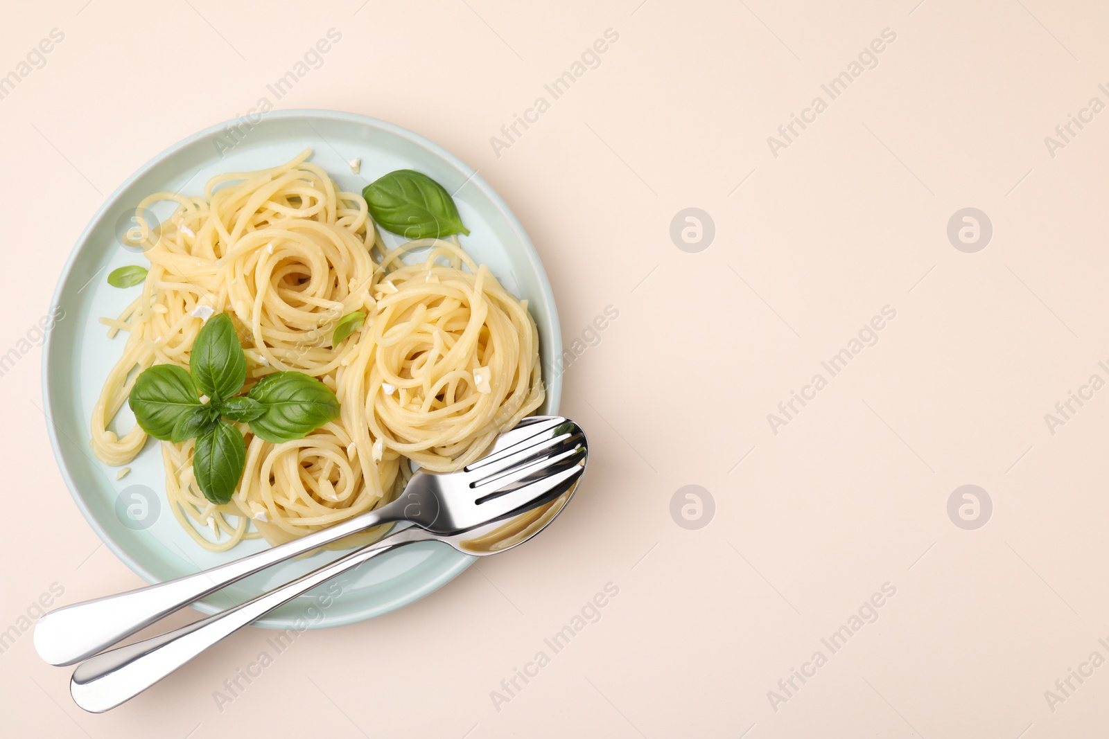 Photo of Delicious pasta with brie cheese and basil leaves on beige table, top view. Space for text
