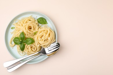 Delicious pasta with brie cheese and basil leaves on beige table, top view. Space for text