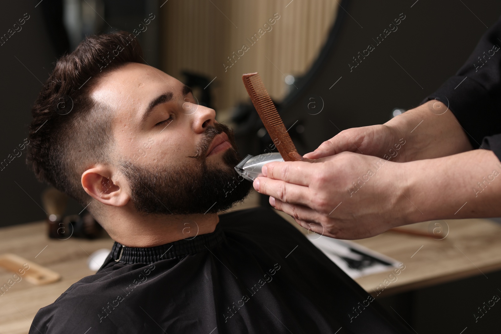 Photo of Professional barber trimming client's mustache in barbershop, closeup