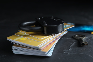 Photo of Credit cards, padlock and key on black slate table. Protection from cyber attack