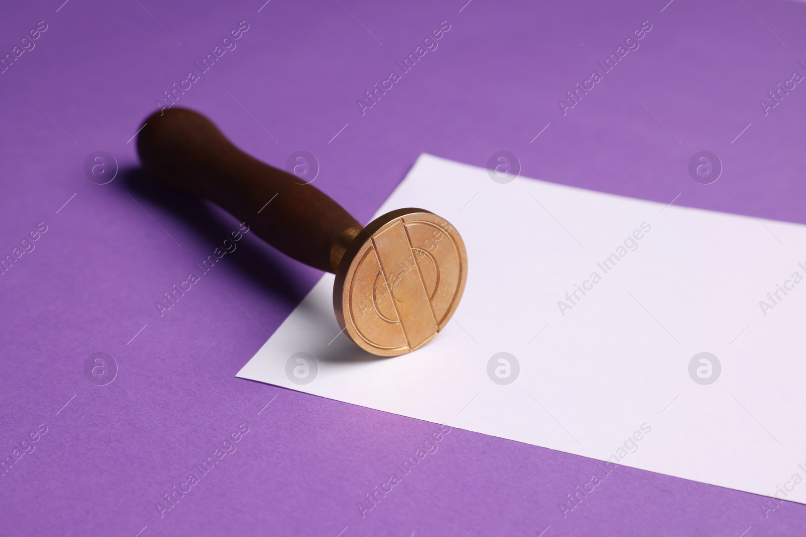 Photo of One stamp tool and sheet of paper on purple background, closeup