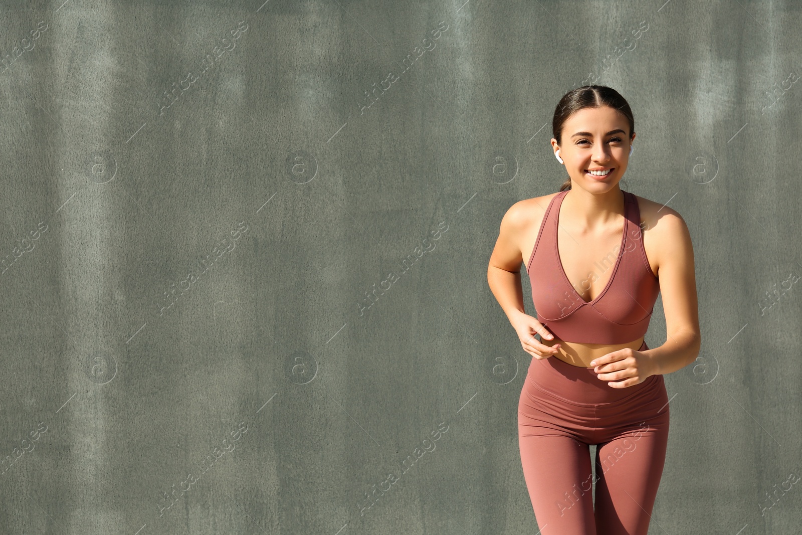 Photo of Happy young woman in stylish sports wear running on grey background. Space for text