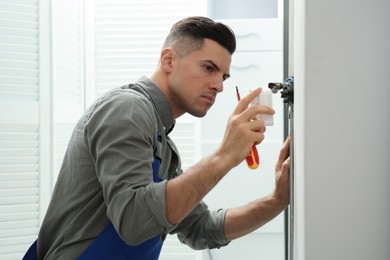 Photo of Professional electrician with screwdriver repairing light switch indoors