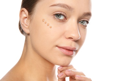 Portrait of young woman with liquid foundation on her face against white background